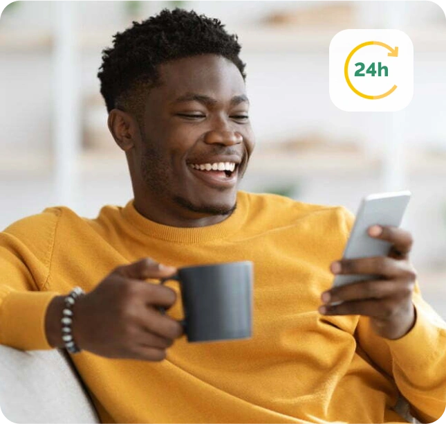 Smiling man holding a mug while using his phone and viewing personal loan options available 24/7 through Fast Loan Advance.